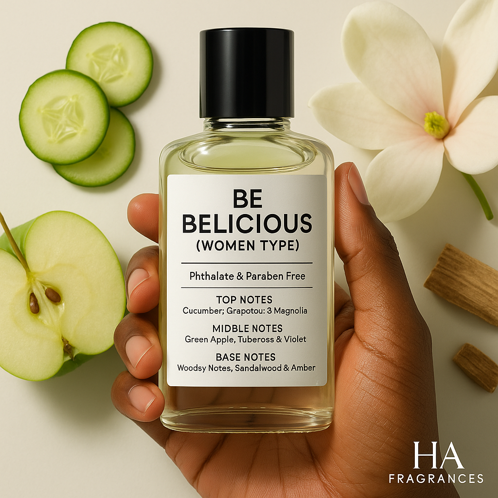 A bottle of Be Delicious (Women Type) Body Oil held by a dark-skinned hand, surrounded by green apples, cucumber slices, magnolia petals, and soft amber, with the HA Fragrances logo in the corner.