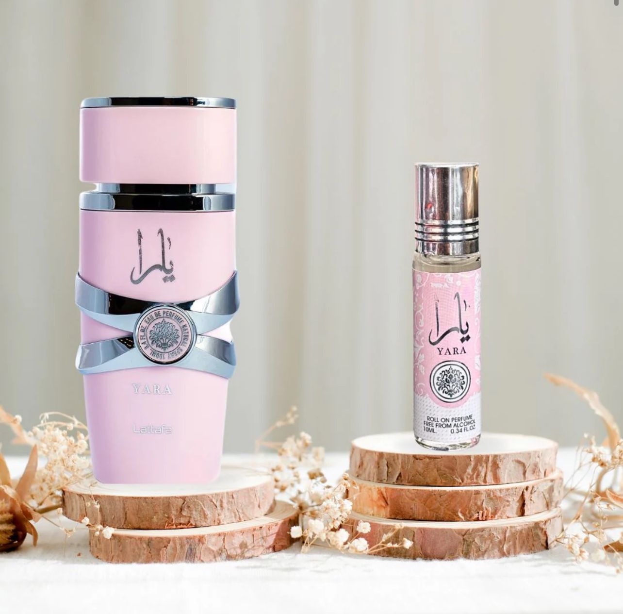 Lattaa Yara perfume set displayed on wooden slices with delicate dried flowers, showcasing a pink spray ottles with silver accents and a roll-on perfume in matching pink pakaging.