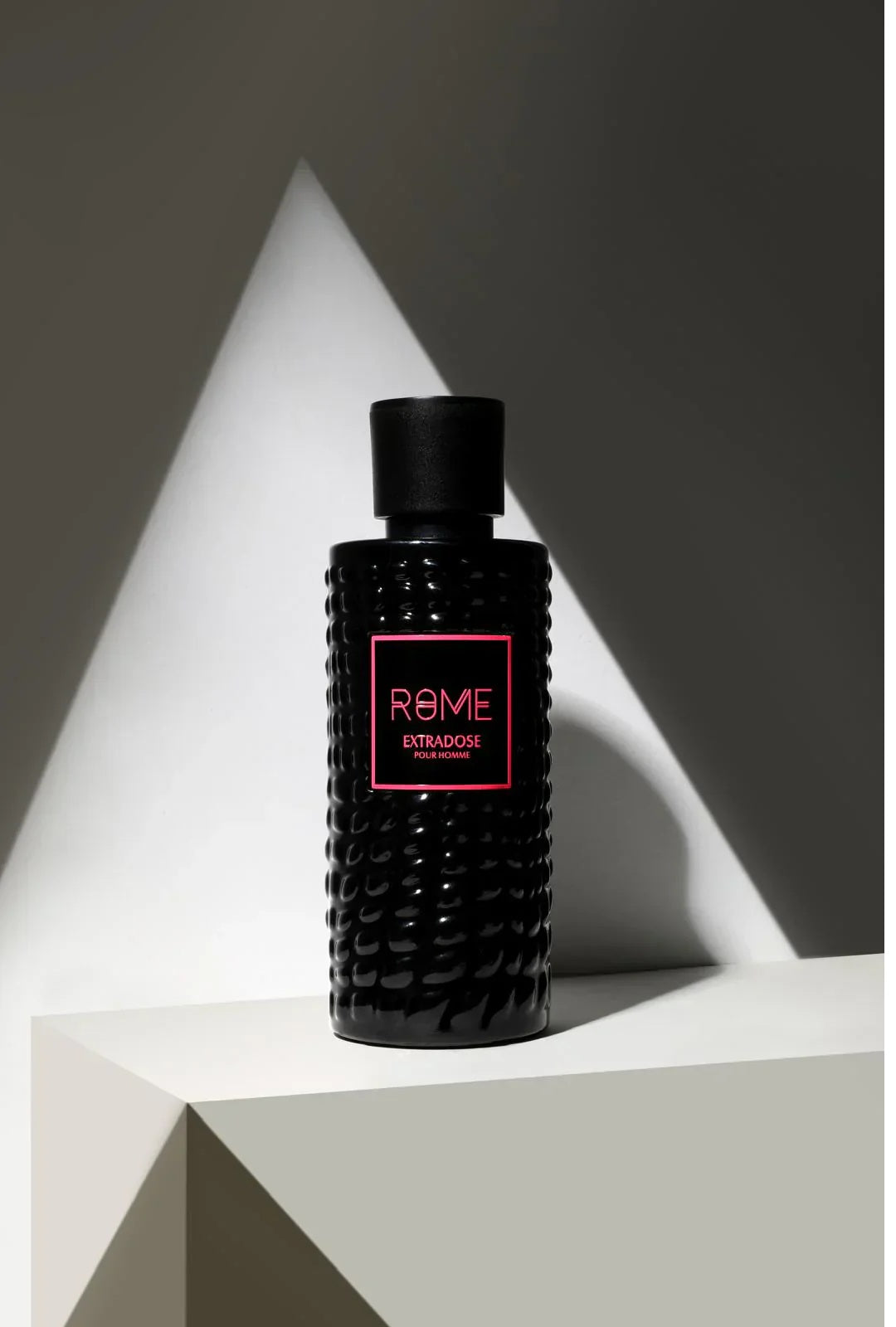 Rome Extradose Eau de Parfum by Bharara Mast Perfume – elegant black textured bottle with pink label under dramatic lighting, luxury men’s amber fougère fragrance.