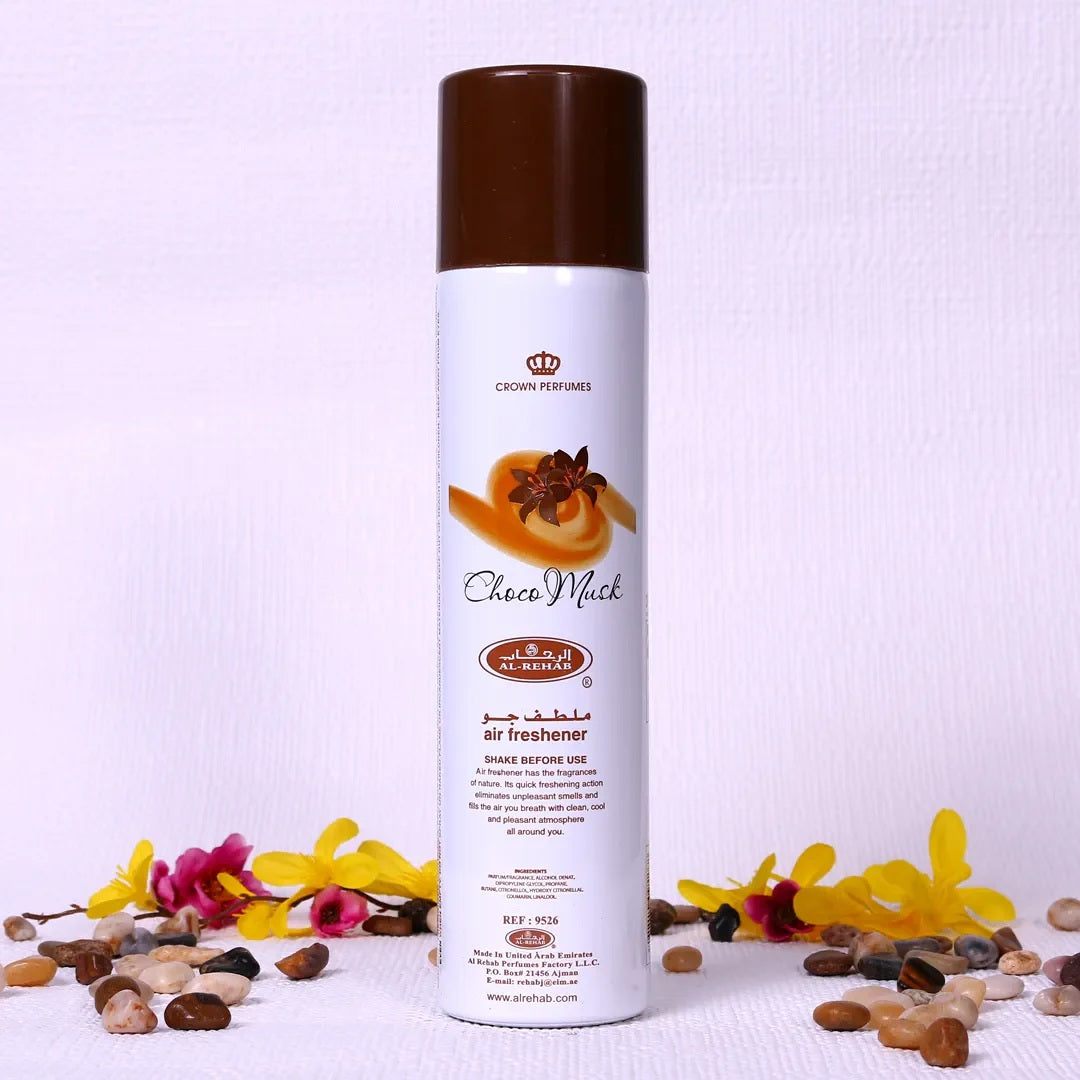 Choco Musk Air Freshener by Al Rehab – 300ml can surrounded by decorative flowers and stones, perfect for creating a warm and inviting atmosphere.