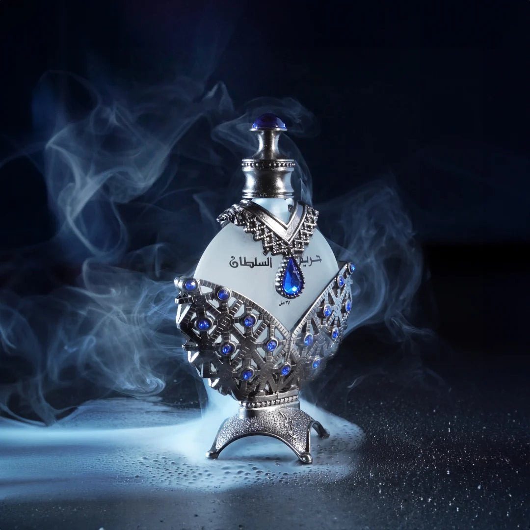 Hareem Al Sultan Blue Perfume Oil by Khadlaj displayed dramatically with smoky effects, showcasing its elegant silver and blue bottle design.