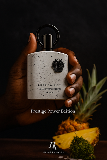 Dark-skinned hand holding Afnan Supremacy Collector’s Edition perfume bottle with pineapple slices and amber tones in the background, featuring HA Fragrances logo and text overlay ‘Prestige Power Edition