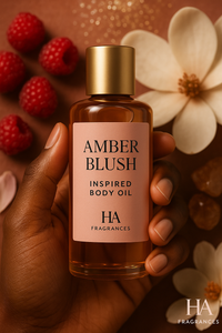 Hand holding a bottle of 'Amber Blush' body oil with raspberries and flowers in the background