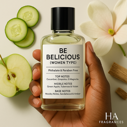A bottle of Be Delicious (Women Type) Body Oil held by a dark-skinned hand, surrounded by green apples, cucumber slices, magnolia petals, and soft amber, with the HA Fragrances logo in the corner.