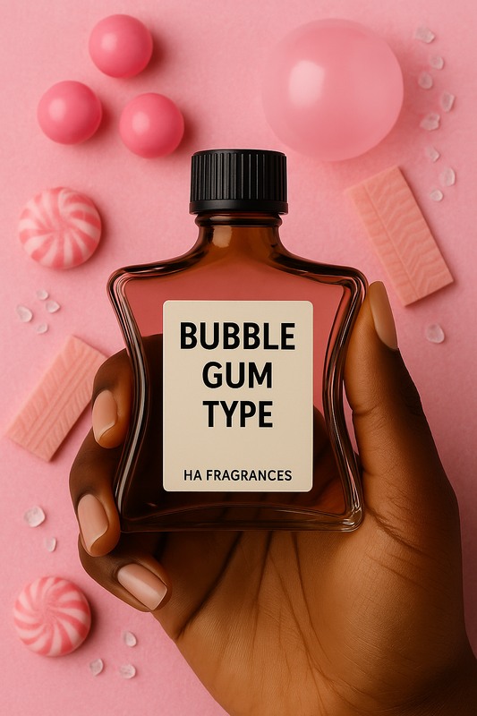 A dark-skinned hand holds a brown glass bottle labeled “Bubble Gum Type – HA Fragrances” against a pink background with bubble gum pieces, round candies, peppermint swirls, and sugar crystals.