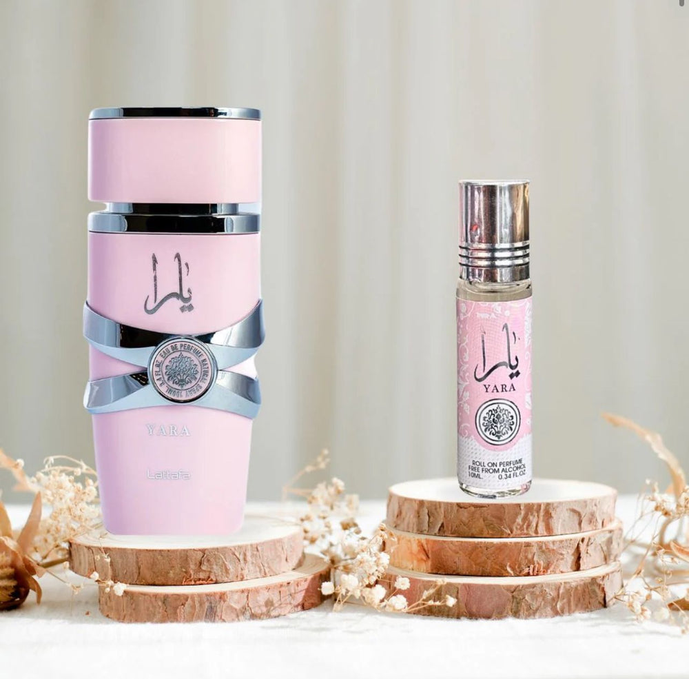 Lattaa Yara perfume set displayed on wooden slices with delicate dried flowers, showcasing a pink spray ottles with silver accents and a roll-on perfume in matching pink pakaging.