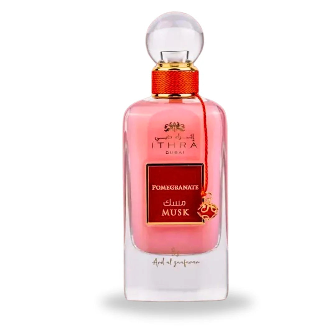 A luxurious pink glass bottle of Pomegranate Musk from the Ithra Dubai Collection, featuring gold and red detailing with an elegant charm by Ard Al Zaafaran.