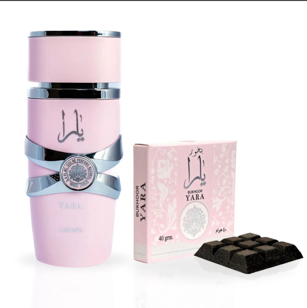 A pink Yara Eau de Parfum bottle with silver details next to a Yara Bukhoor box and charcoal-like Bukhoor pieces.