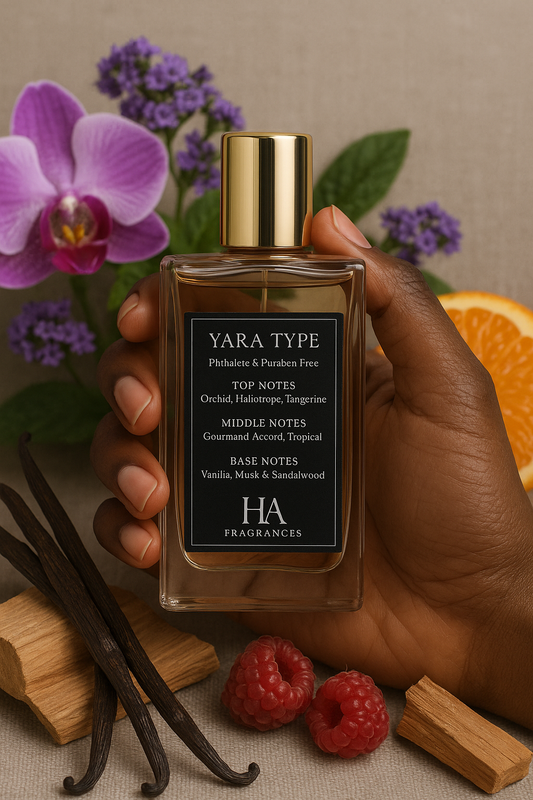 Hand holding a Yara Type perfume bottle with vanilla beans, raspberries, and an orange in the background.