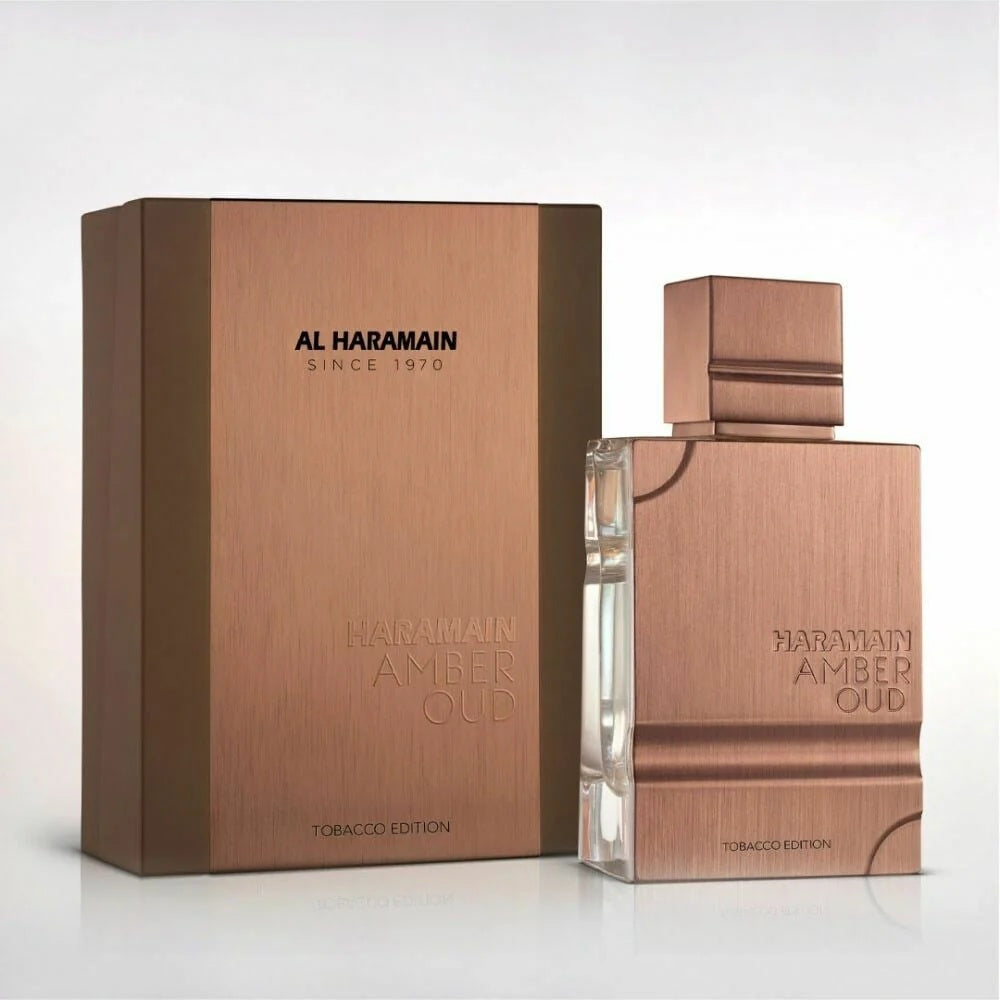 Haramain Amber Oud Tobacco Edition - 100ML EDP bottle alongside its sleek copper packaging, symbolizing luxury and sophistication.