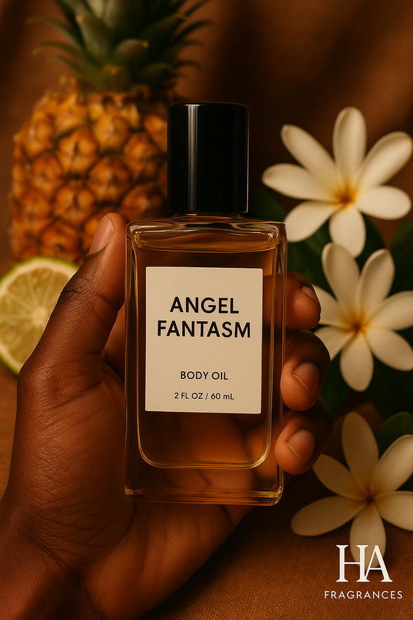 Angel Fantasm body oil held by a dark-skinned hand with pineapple, lime, and tropical white flowers in the background, HA Fragrances logo in the corner.