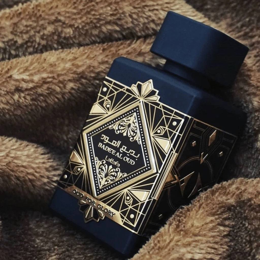 Oud For Glory Bade’e Al Oud by Lattafa perfume bottle with intricate gold detailing resting on a soft fabric background.