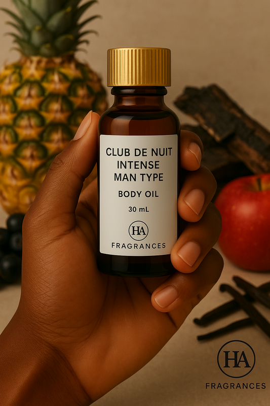 Dark-skinned hand holding HA Fragrances 30ml Club De Nuit Intense Man Type body oil bottle, with pineapple, apple, vanilla sticks, and blackcurrant in the background – bold, masculine, and woody fragrance.
