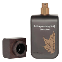 La Yuqawam Tobacco Blaze by Rasasi with its stylish black bottle featuring a golden leaf design and wooden cap removed to reveal the spray nozzle.