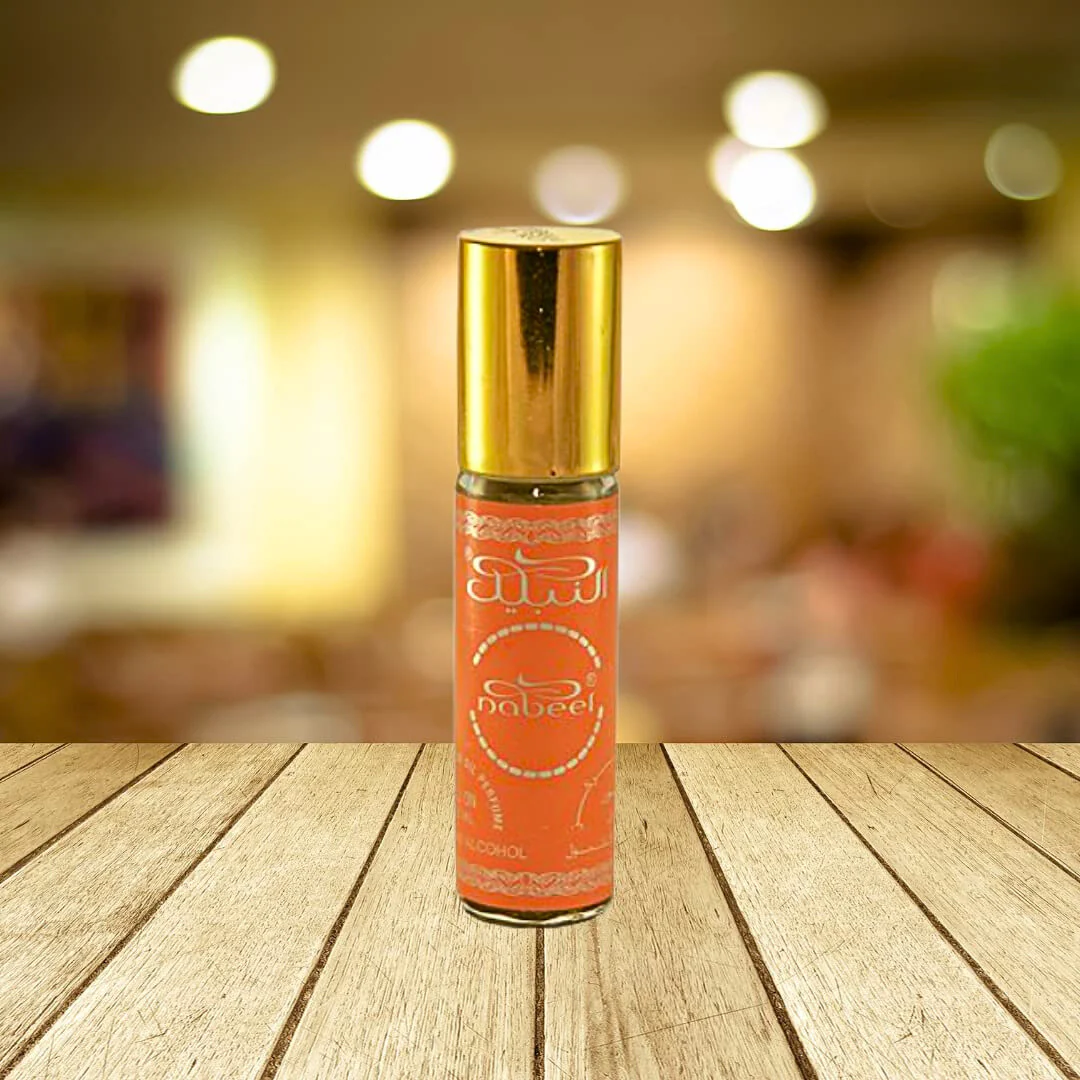 Nabeel 6ml roll-on perfume oil bottle with a vibrant orange design and golden cap, placed on a wooden surface with a blurred background.