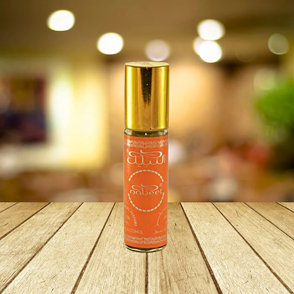 Nabeel 6ml roll-on perfume oil bottle with a vibrant orange design and golden cap, placed on a wooden surface with a blurred background.