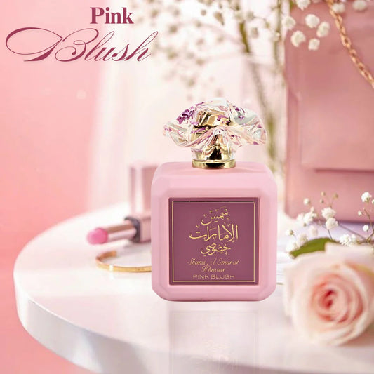 Pink Blush Shams Al Emarat perfume bottle on elegant vanity table with roses and makeup accessories