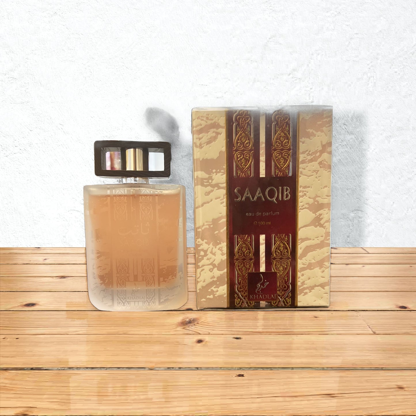 Saaqib by Khadlaj EDP 100 ml with its frosted glass bottle and ornate packaging on a wooden table.