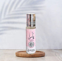 Yara 10ml roll-on perfume oil by Ard Al Zaafaran, featuring a sleek pink floral design with a silver cap, elegantly placed on a wooden coaster.